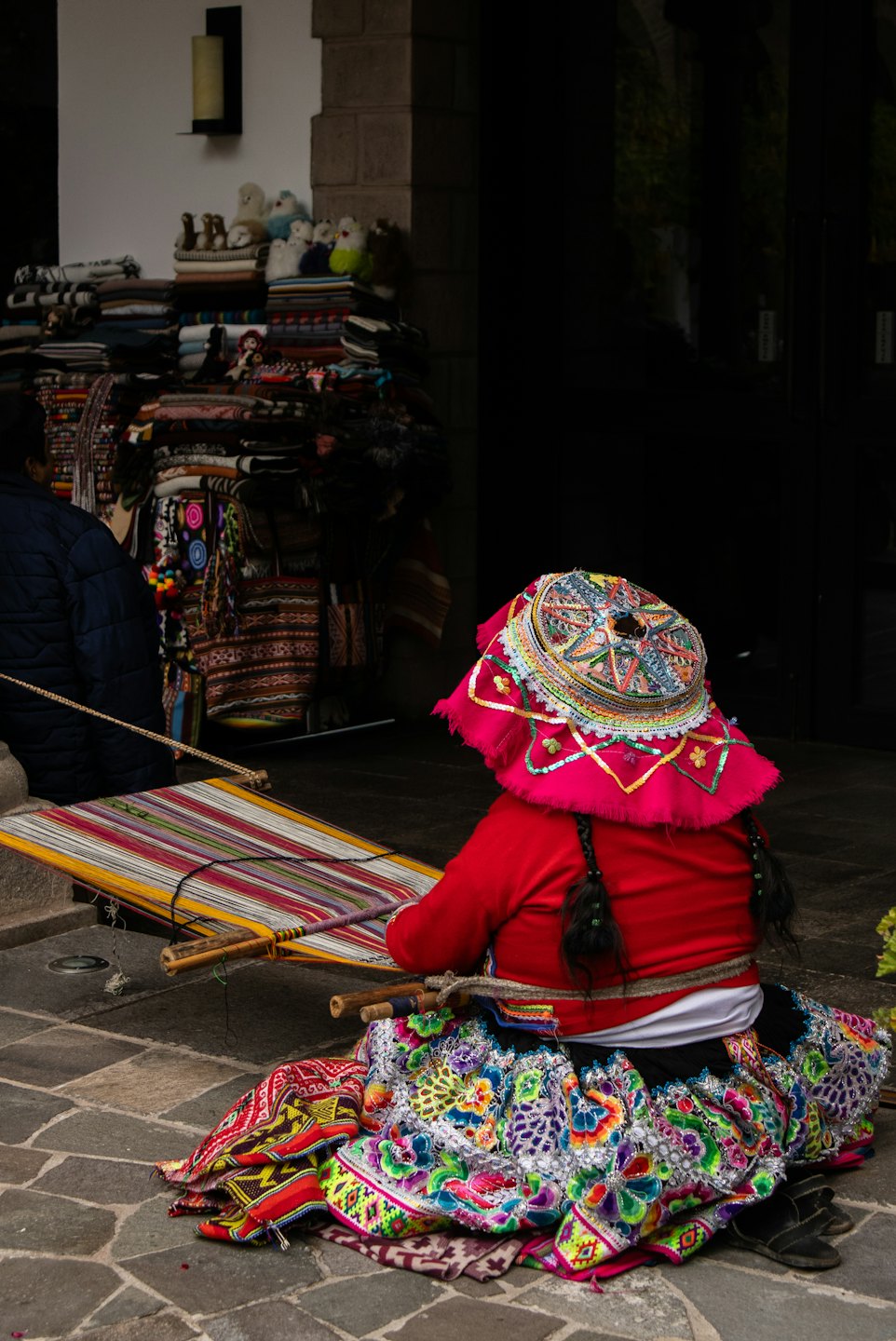 An artisan weaves a colorful textile on a traditional loom.