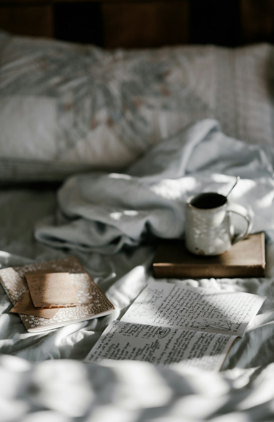 Open notebook with handwritten text on a rumpled bed.